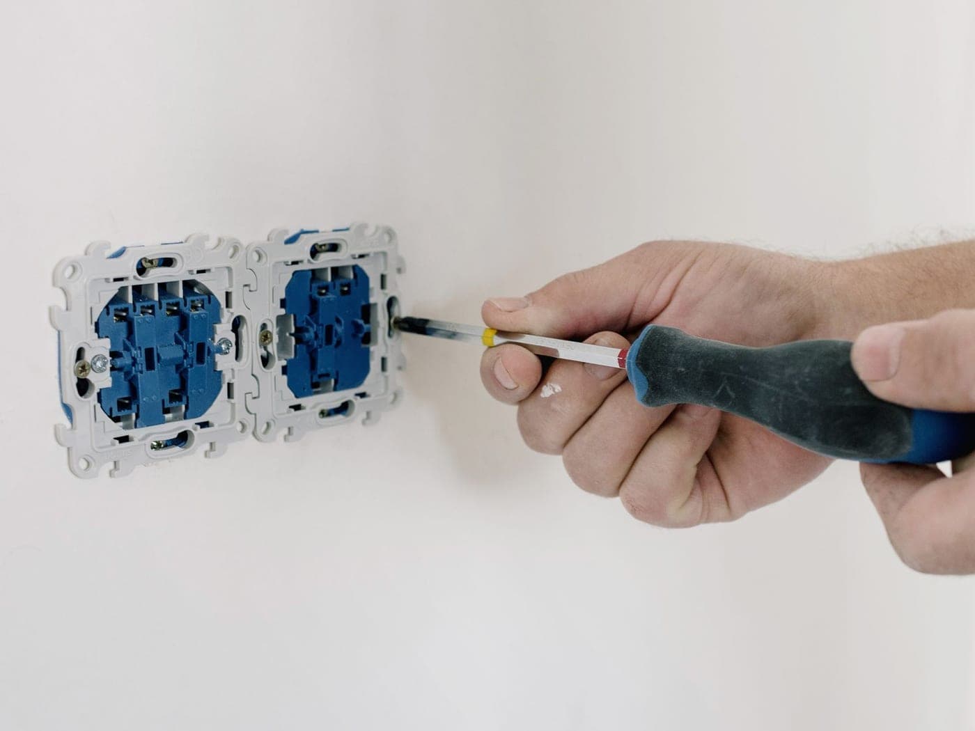 Mano atornillando el mecanismo de un interruptor en la pared